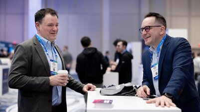 Two men network at a booth on the show floor at HumanX 2025
